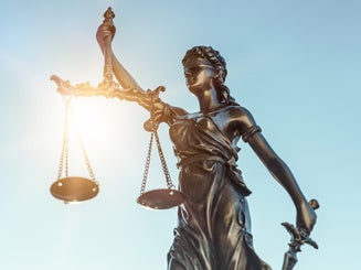 lady of justice statue with sun behind her