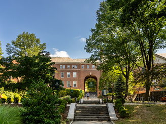 Front of campus with student walking down stairs at Manhattan University