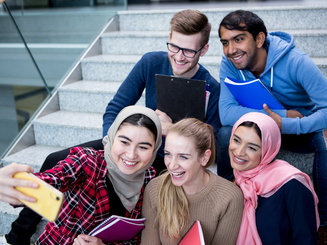 Group of students sitting on the steps taking a selfie