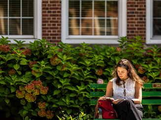 Manhattan University graduate student Sitting on a bench in the Quad