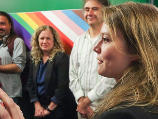 a group of people stand in front of a rainbow colored wall
