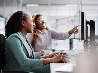 Accounting students in classroom talking and pointing to computer screen