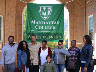 student with family pose for photo in front of family weekend sign