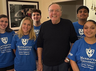 Manhattan University students in blue James Patterson Honors Program shirts pose indoors with alumnus and author James Patterson ’69, all smiling at the camera.