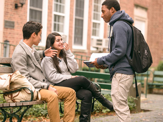 students talk at a bench on campus
