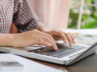 a person's hands typing on a laptop computer