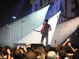 musician stands in the spotlight on a stage with a guitar