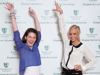 two students pose in front of a photo wall