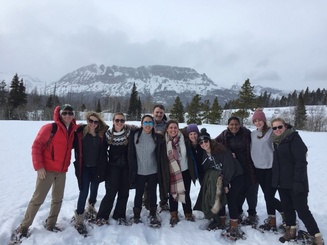 students posing together in the snow with a mountain in the background