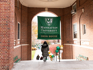 Students walkin underneath the Manhattan University Open House banner on campus.
