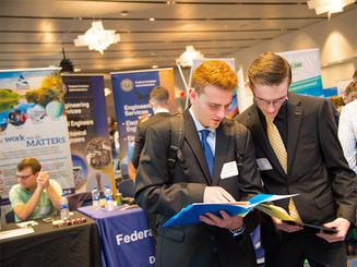 two students share notes at a campus career fair