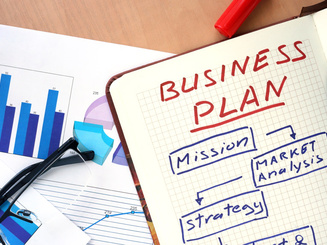 notebook open with the text "Business Plan" written on a page