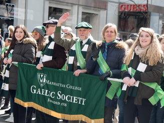 members of the Gaelic society march in a parade with a banner