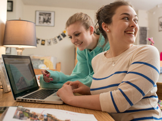 two students at a computer in a shared dorm room