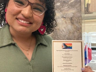The Rainbow Jaspers President holding a program guide for a Pride event
