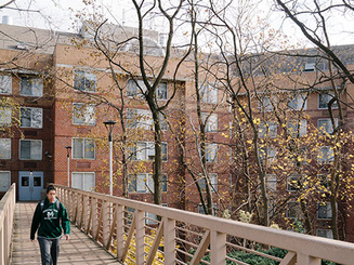 A student walks across a bridge on the Manhattan University campus