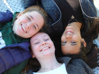 three women posing on the ground with their heads together