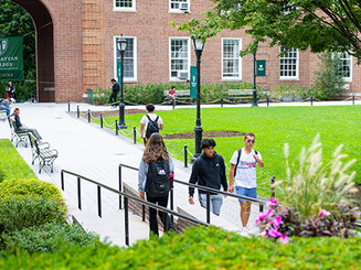 students walk on a paved path on the campus of Manhattan University
