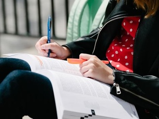 a student highlights in a workbook while seated outside