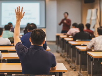 Rear view of audience in raise hand up response for answer the question in a classroom
