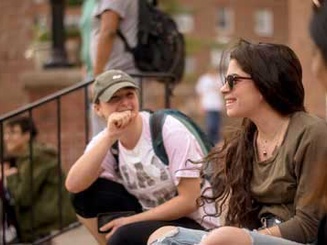 students gather on the steps of a building on campus