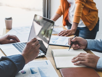 People in group looking at computers and spreadsheets