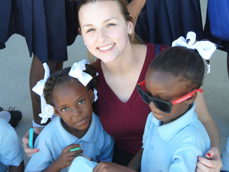a student poses with two young children on a service immersion trip