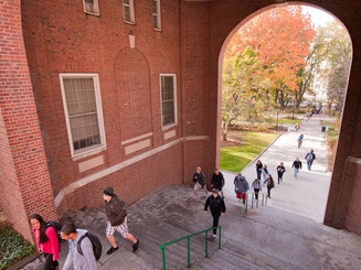 students walk up stairs under a bricked arch