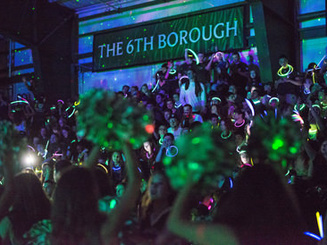 students gather in a dark arena with glow sticks
