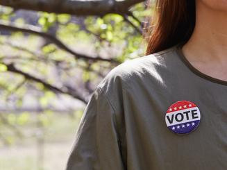 a person wearing a pin that reads Vote
