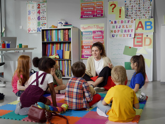 School children with teacher sitting on floor having lesson
