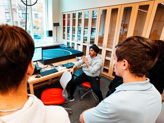 Engineering professor talking with students in a lab while showing an experiment on a screen