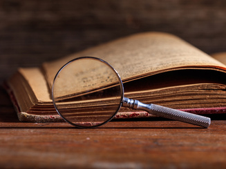 Vintage book and magnifying glass on wooden desk