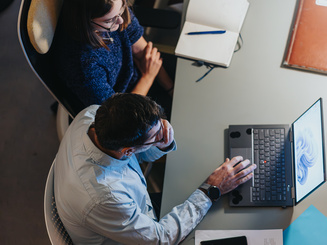 Overhead view of professional team working at a busy office desk with tech gadgets.