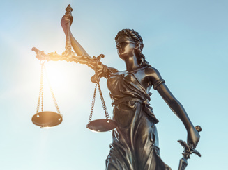 lady of justice statue with sun behind her