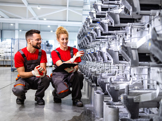 Mechanical engineers checking parts and productivity of new assembled machine inside the factory.