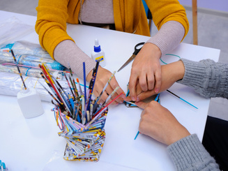 Therapist hands helping person with special needs make handmade souvenir using glue and paper