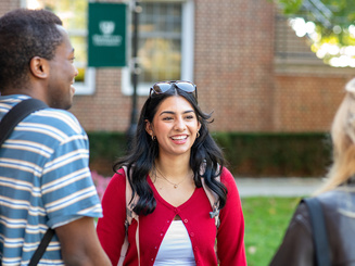 Students smiling and talking as they are walking across campus