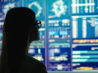 The businesswoman in glasses standing near the display looking at data and analytics
