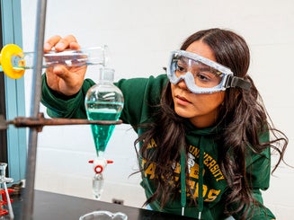 Photo of Maria Azevedo '26 in a chemistry lab with laboratory equipment