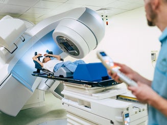Cancer treatment in a modern medical private clinic or hospital with a linear accelerator. Professional doctors team working while the woman is undergoing radiation therapy for cancer