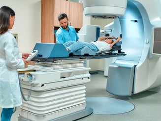 A young woman is undergoing radiation therapy for cancer under the supervision of doctors in a modern cancer hospital. Cancer therapy, advanced medical linear accelerator.
