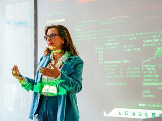 Photo of professor teaching in the Bloomberg Lab with data screen projecting on her and the wall