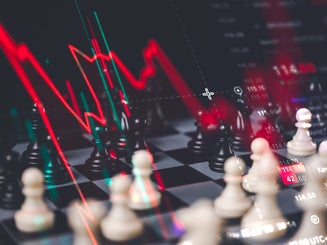 Stock market crash and financial crisis concept showing a chess board with a steep red downward trend line chart overlay