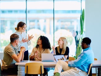 business professionals brainstorming and discussing project data during a corporate meeting at a long table in a bright office