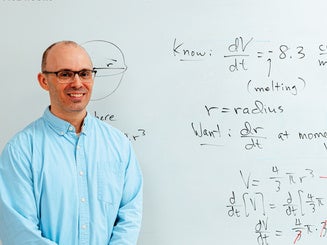 Photo of Matthew Jura, Ph.D. in a classroom with equations on the back wall