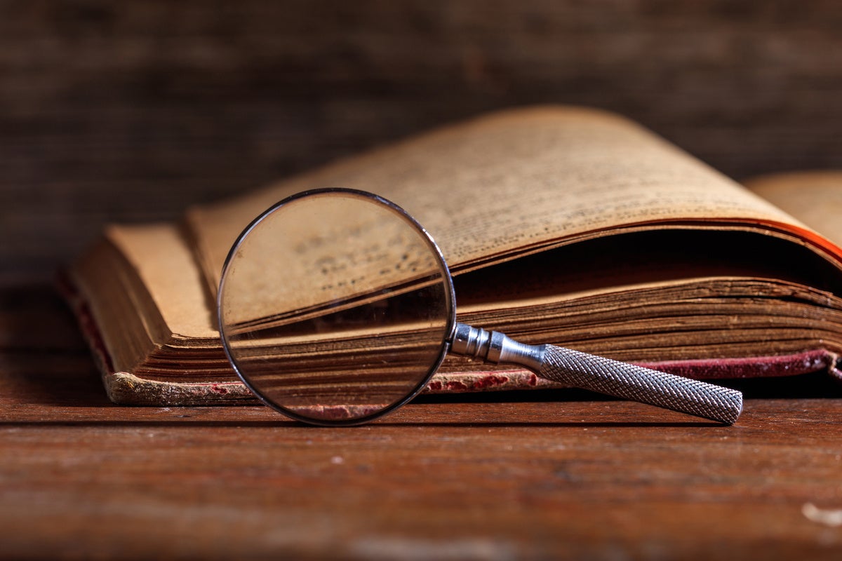 Vintage book and magnifying glass on wooden desk