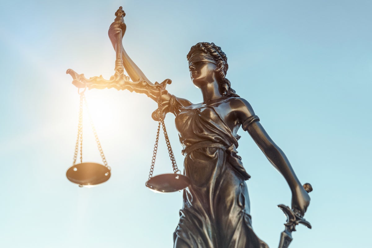 lady of justice statue with sun behind her