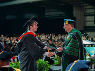 A male student shaking hands with President Riverso after receiving his diploma 