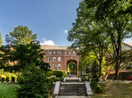 Front of campus with student walking down stairs at Manhattan University